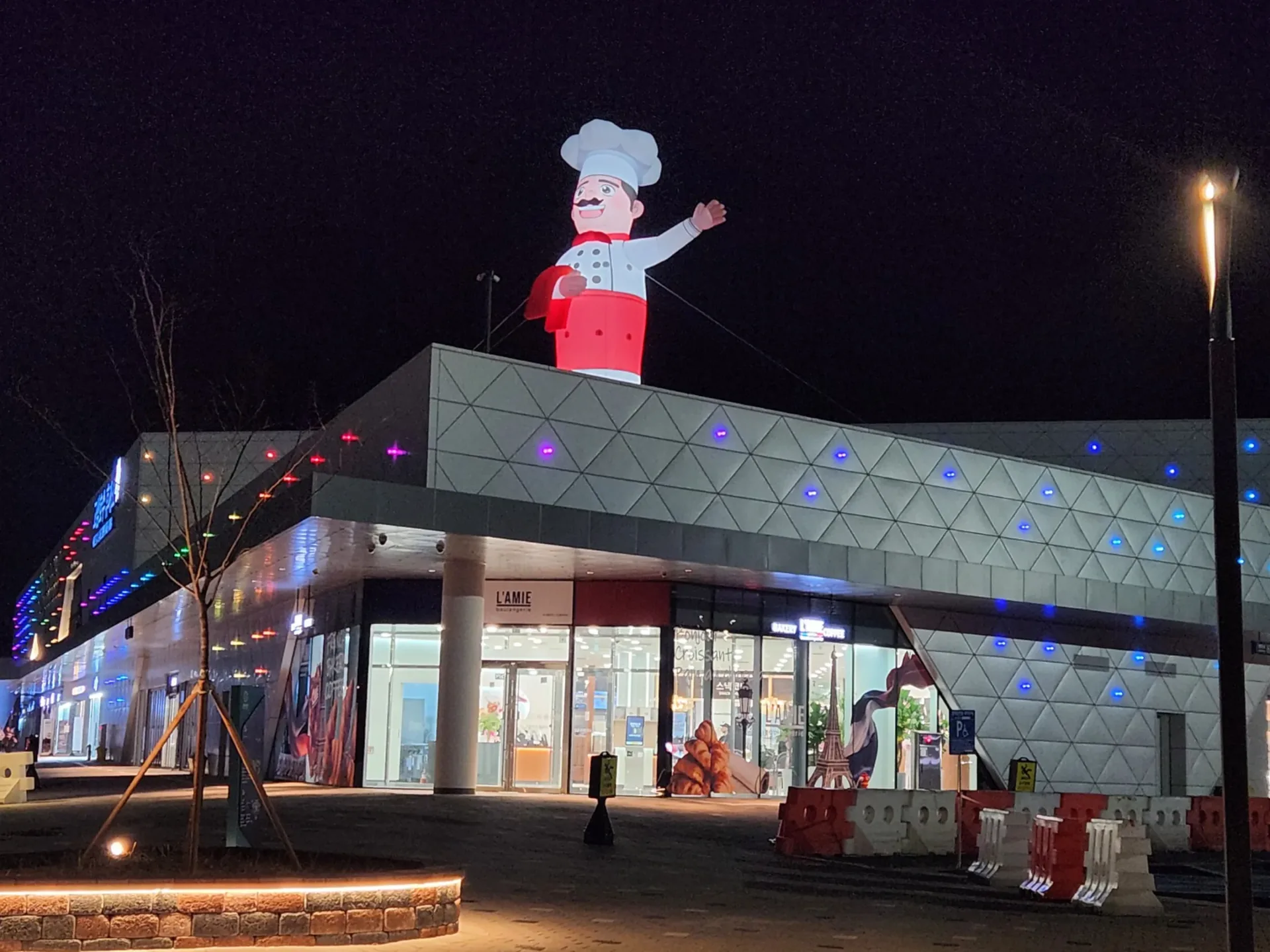 고속도로 휴게소 건물 옥상 위에 설치된 대형 캐릭터 조형물과 파사드 포인트조명 야간 전경