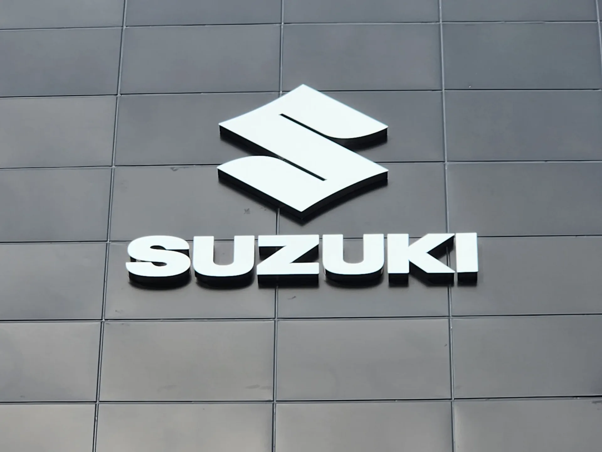 쇼룸 외벽에 설치된 SUZUKI 채널 로고 사이니지 야간 점등 모습